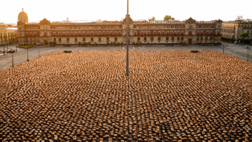 Fotografía aérea masiva de miles de personas desnudas acostadas en la Plaza de la Constitución o Zócalo de la Ciudad de México, instalación artística de Spencer Tunick frente al Palacio Nacional al amanecer.