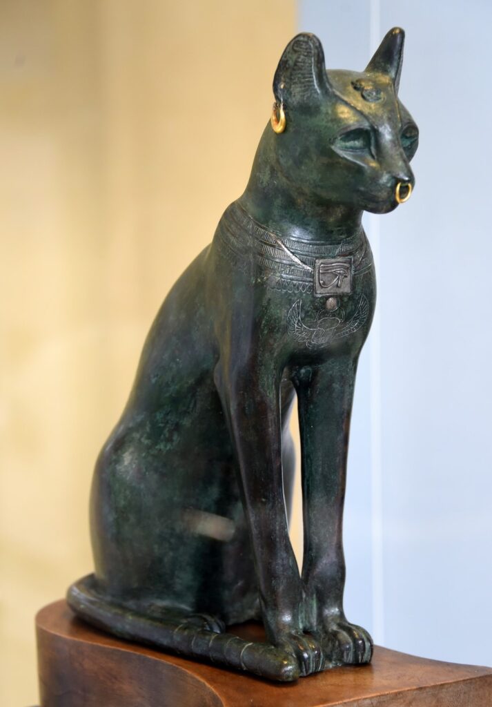 Bastet en forma de gata en el Gato de Gayer-Anderson, escultura egipcia de bronce adornada con joyas y amuletos protectores.