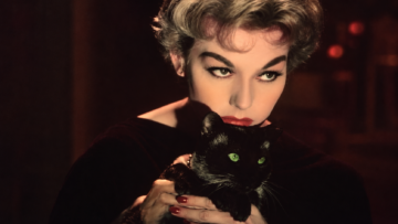 Kim Novak sostiene al gato Pyewacket en Bell, Book and Candle, entre sombras y tonos oscuros que evocan brujería y sensualidad.