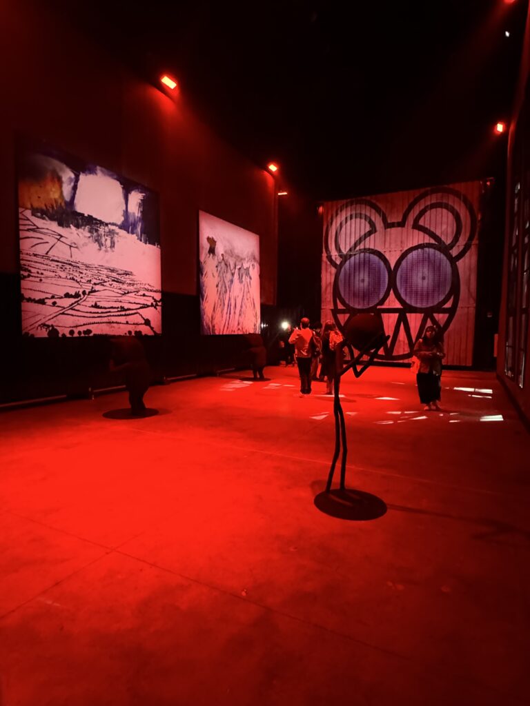 Visitantes recorren una instalación artística de la exposición de Radiohead Kid A Mnesia iluminada en rojo.