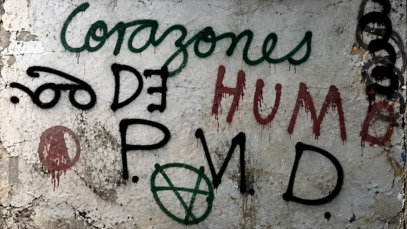Pared desgastada con las pintas «Corazones de humo» y «P.N.D.» en verde, rojo y negro, en una imagen de la película.