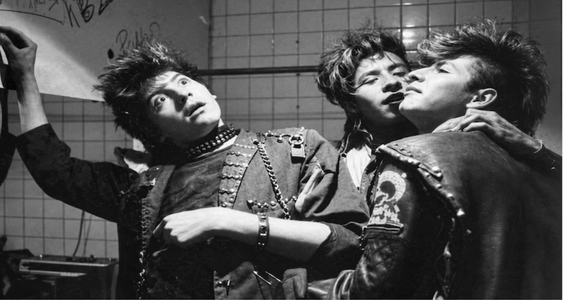 Tres jóvenes con estética punk, cadenas y estoperoles en una escena de Corazones de humo, película de Enrique Estevez.